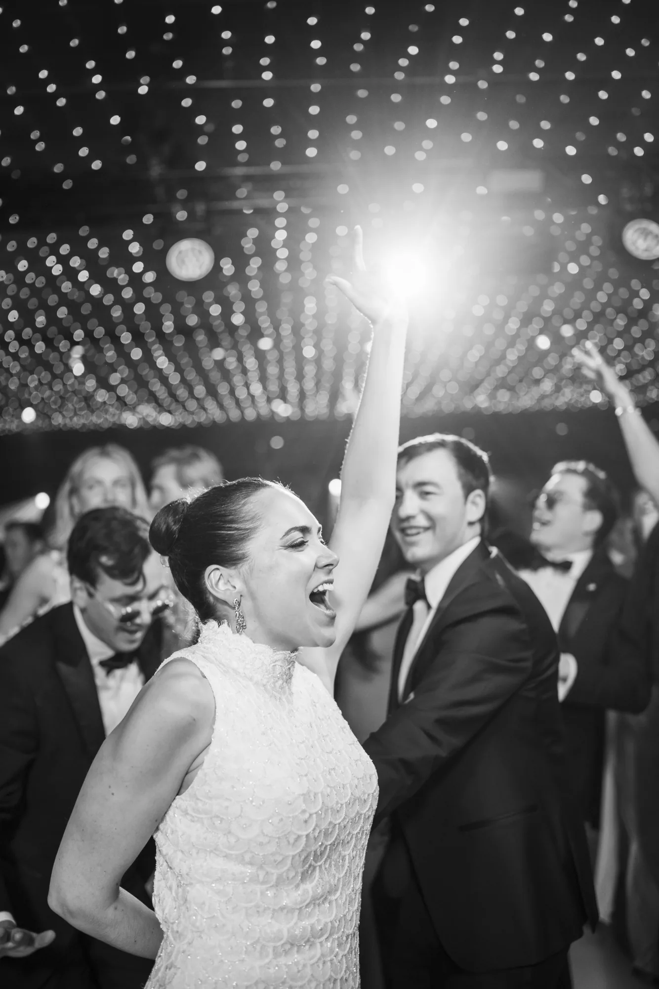 Black and white photo of the bride dancing with a sparkler raised