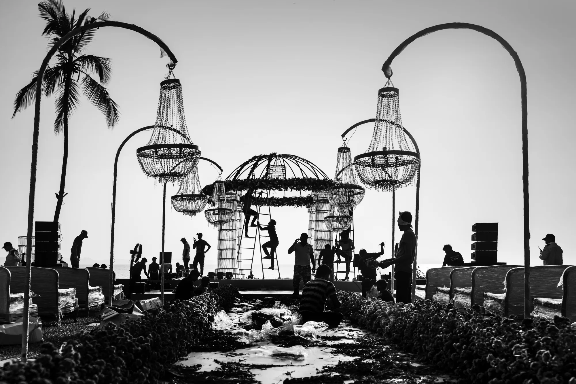 Black and white view of chandelier arches and palms over a seaside terrace