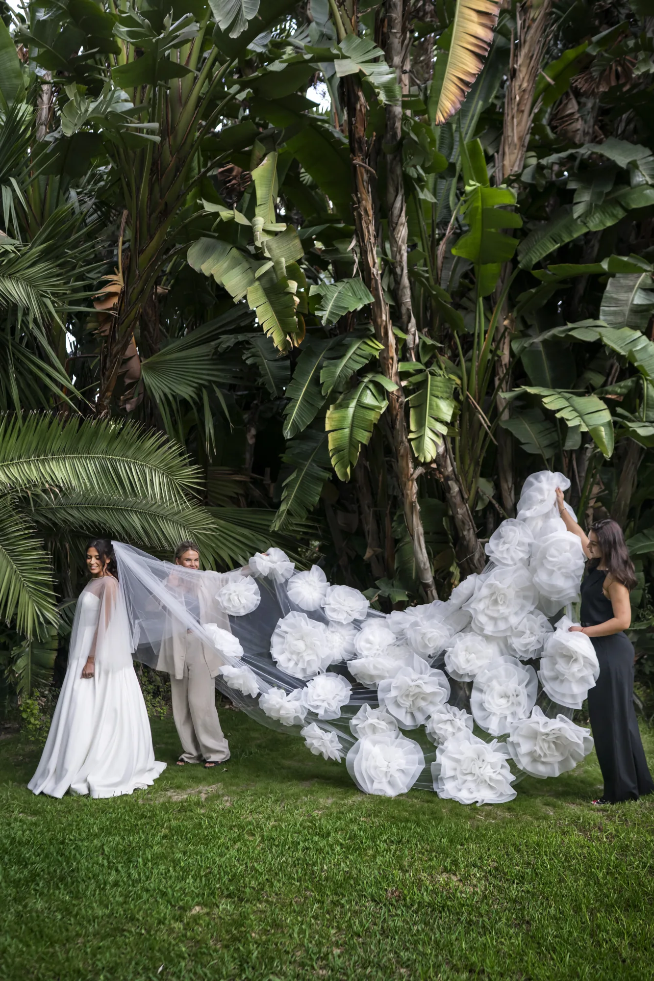 Bride beside towering white flower sculptures in a tropical garden