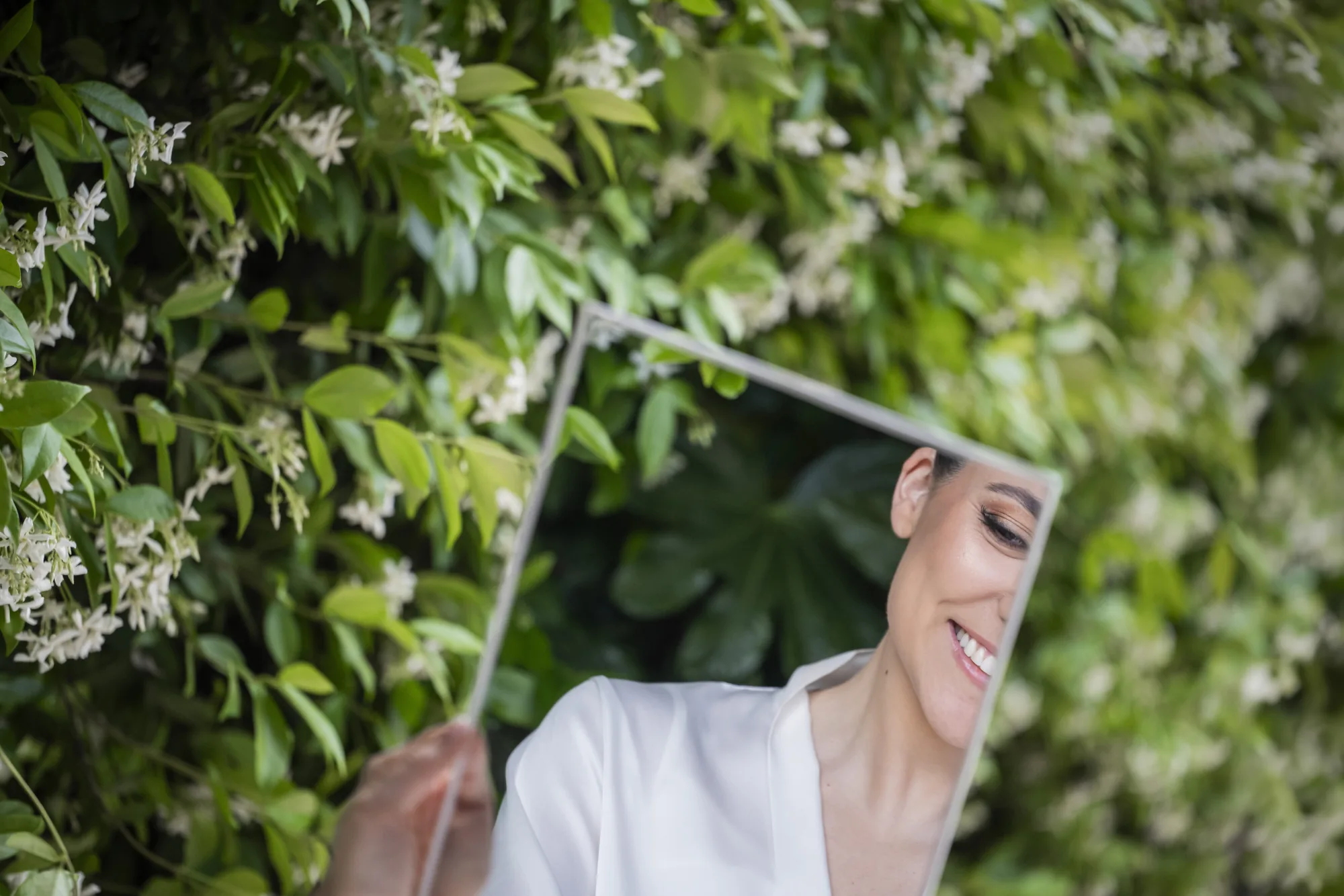 Bride laughing beneath her veil among jasmine