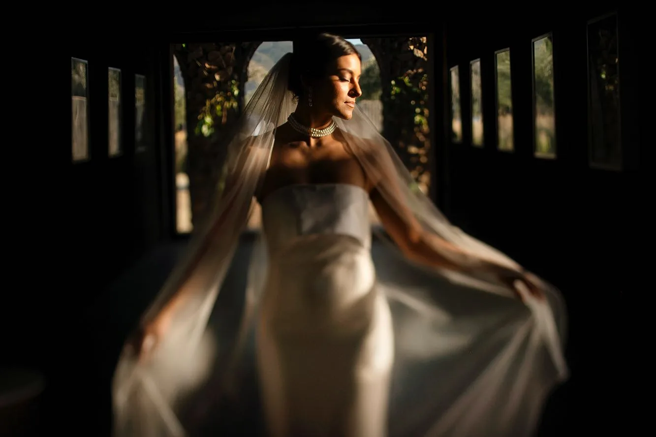 Bride lifting her skirt as she turns in a dark hall