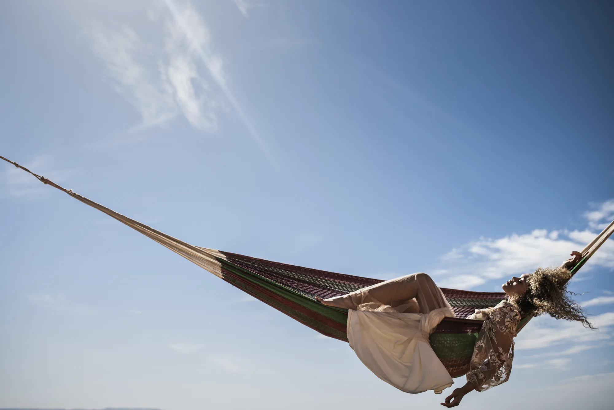 Bride lying in a hammock against an open sky