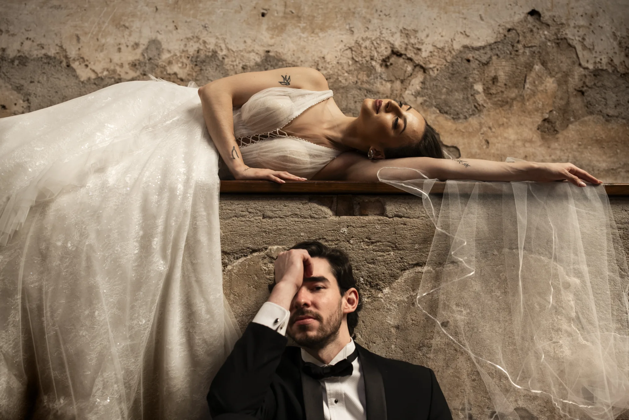 Bride reclining on a stone ledge with the groom resting below her