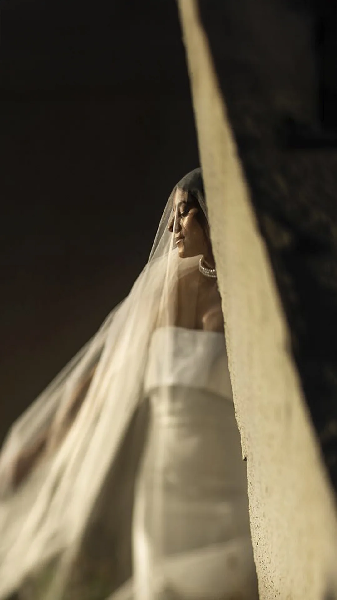 Bride's veil caught in a beam of light in a dark room