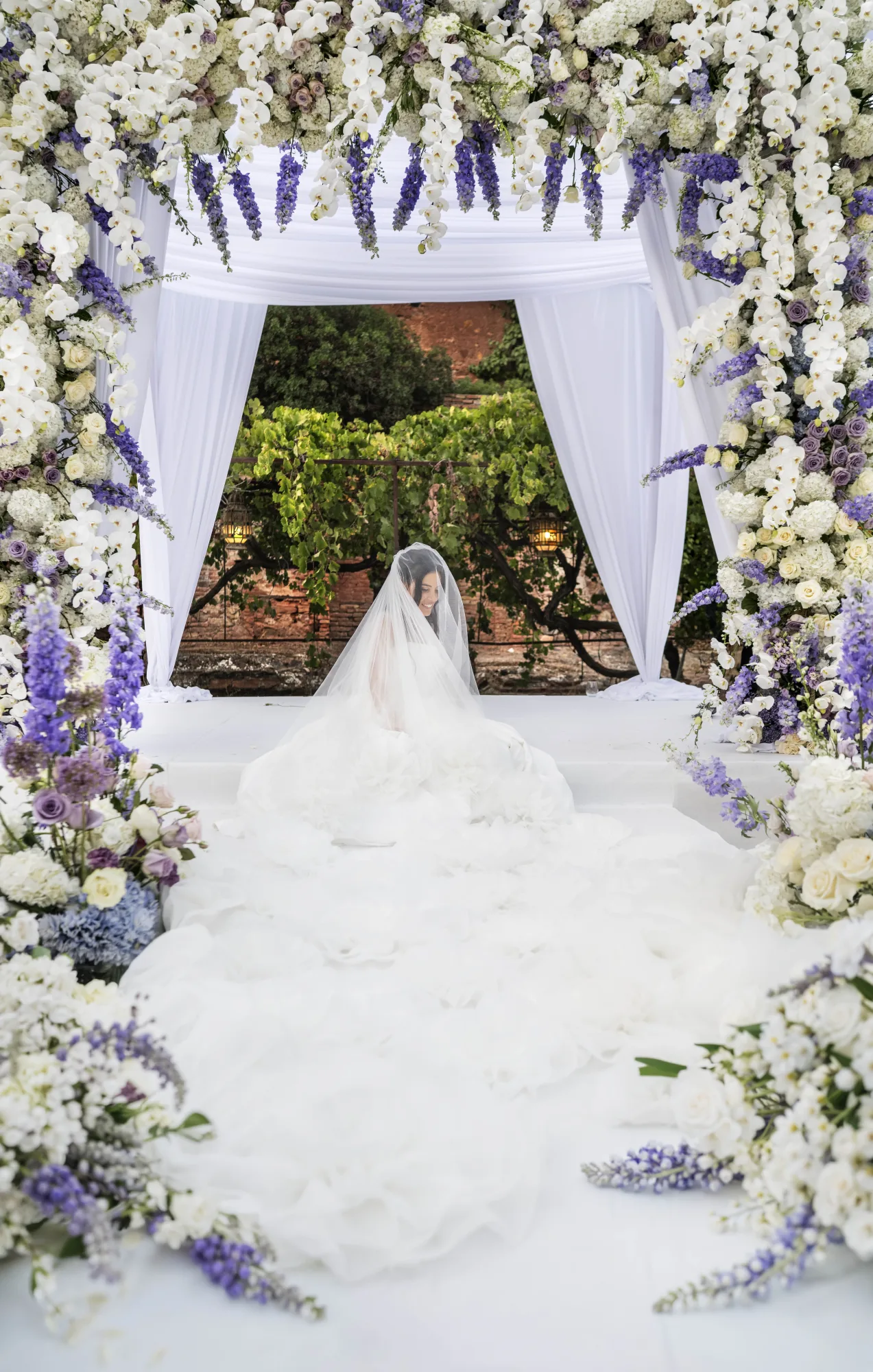 Bride under a canopy of white and lilac flowers