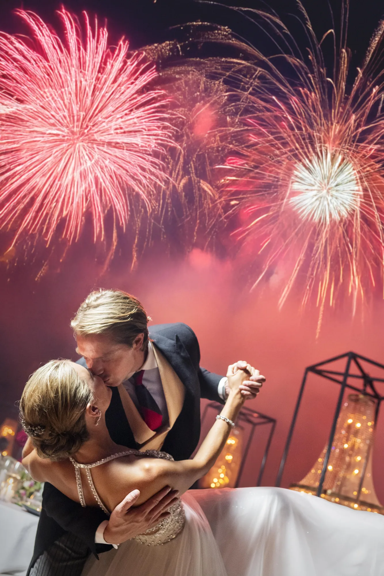Couple dancing beneath red fireworks
