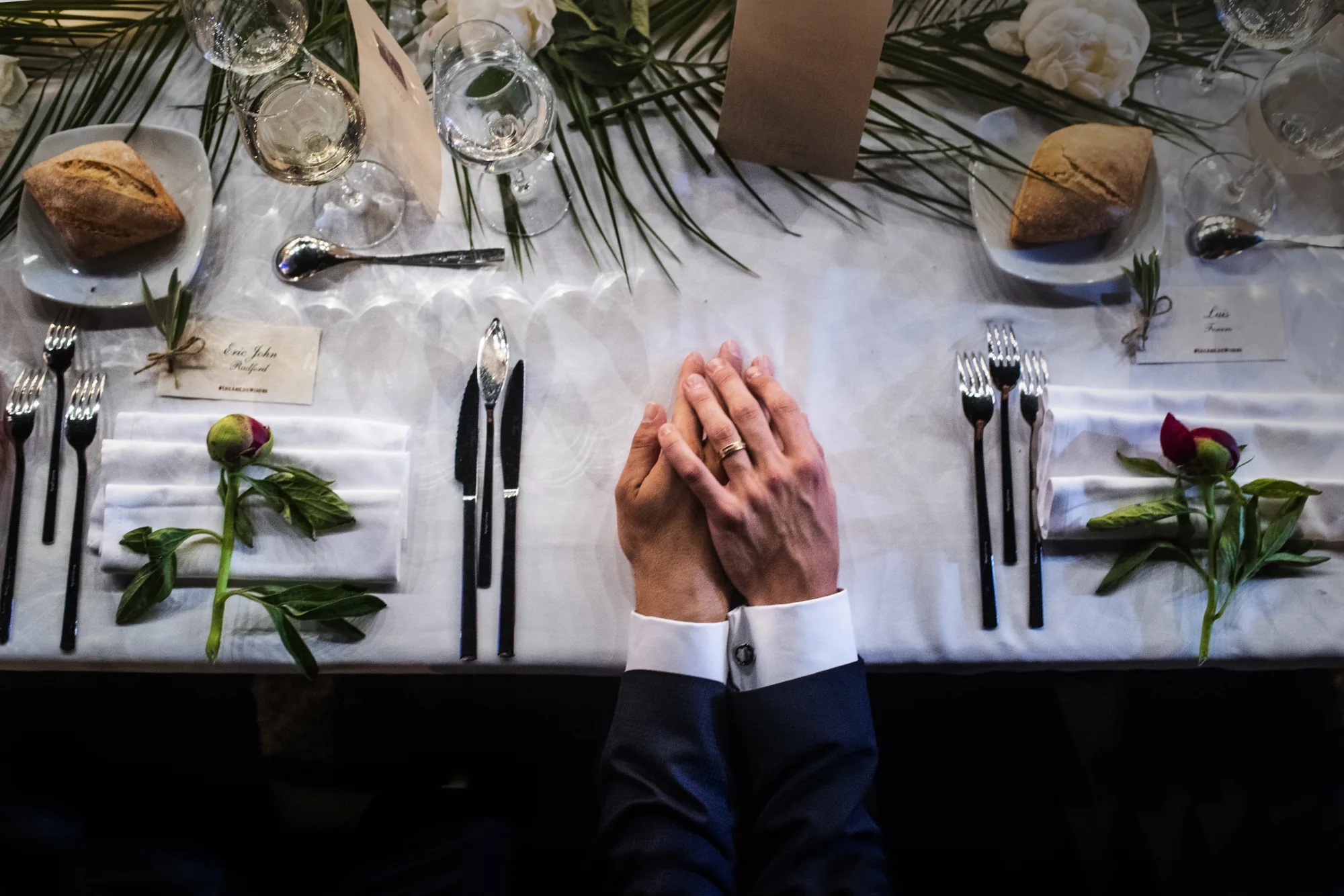 Couple's hands with their rings resting on a set reception table