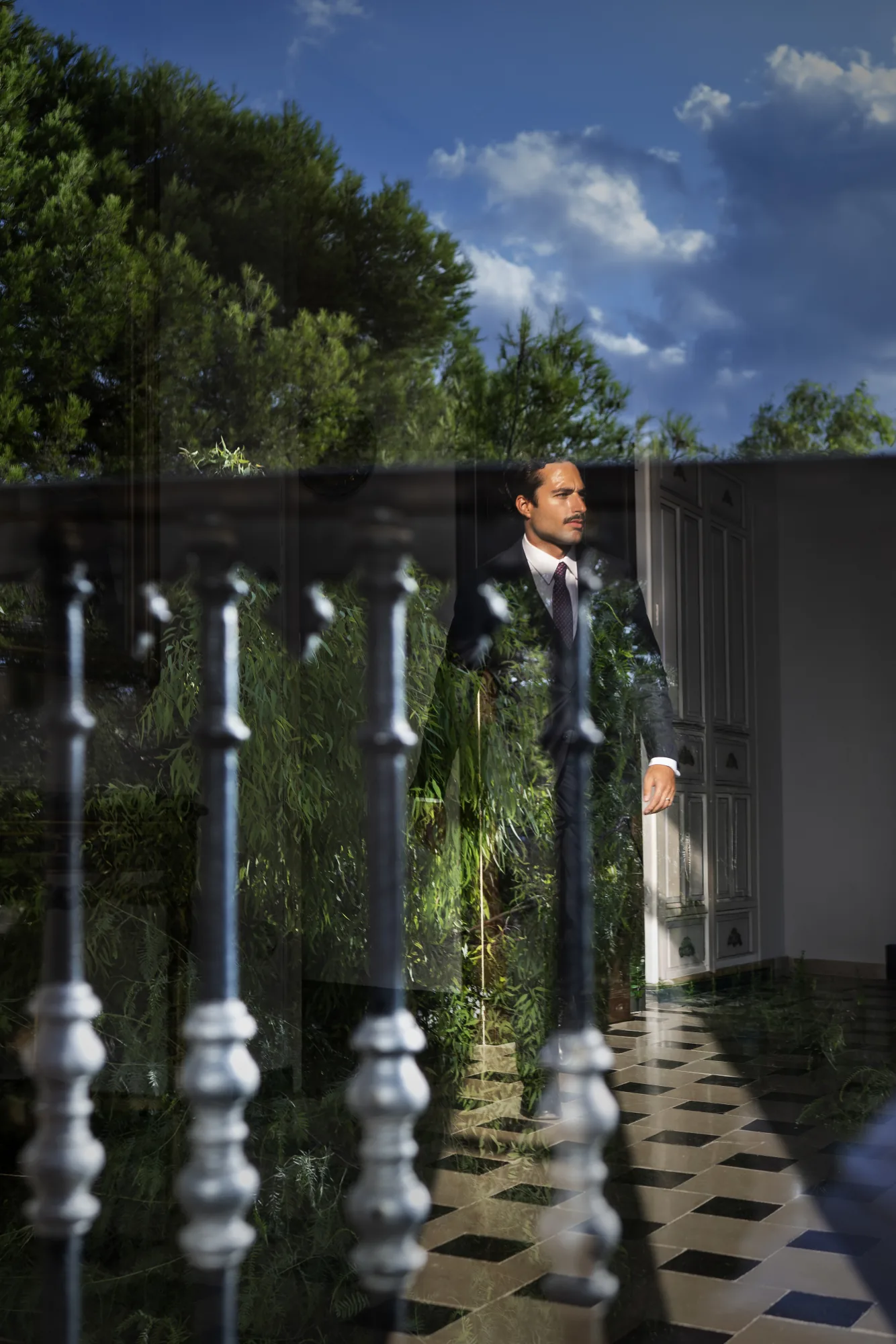 Groom beside a white balustrade in a garden