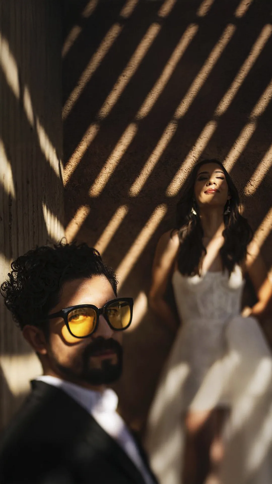 Groom in yellow sunglasses and the bride in striped shadows
