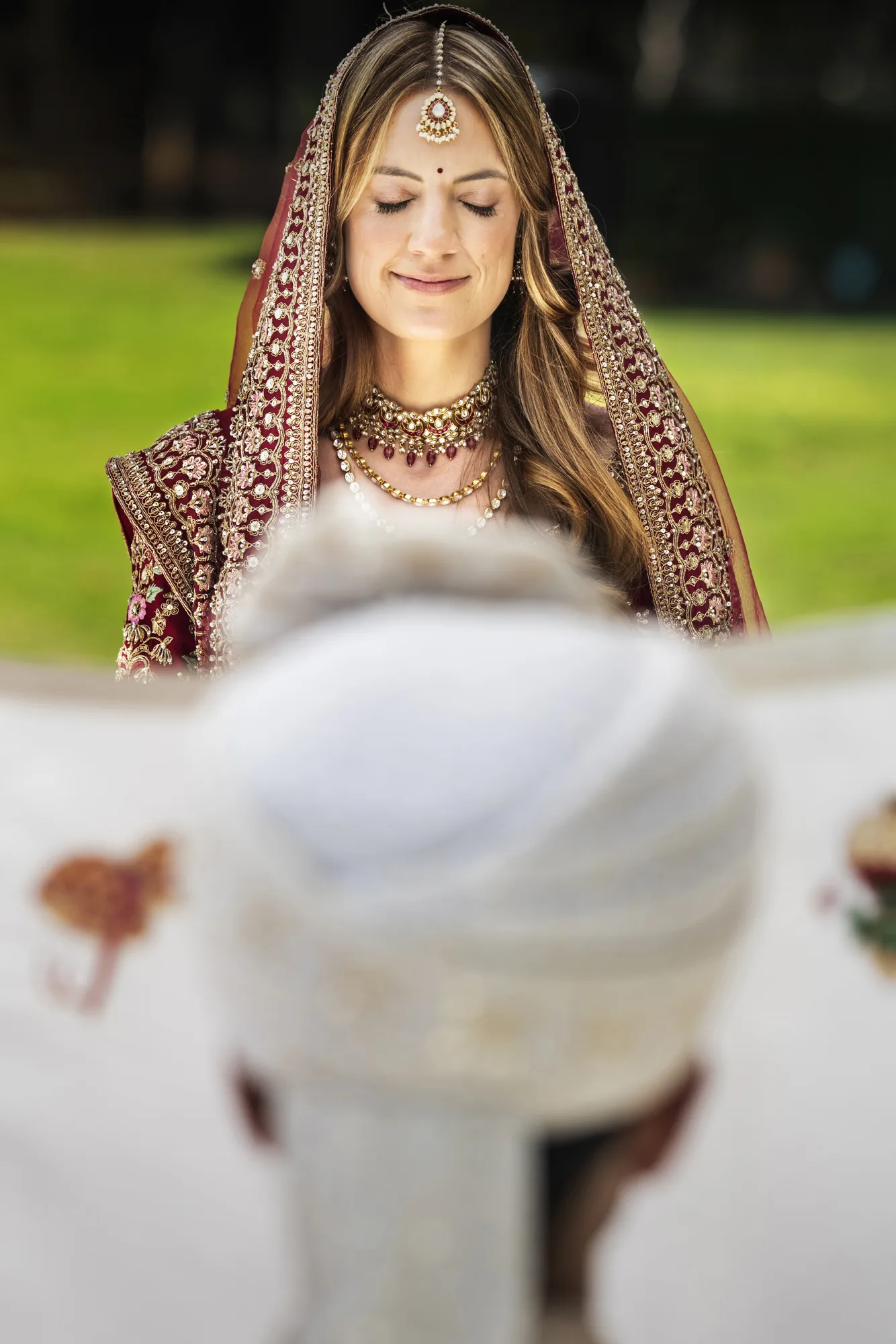 Indian bride smiling down, the groom's turban in the foreground