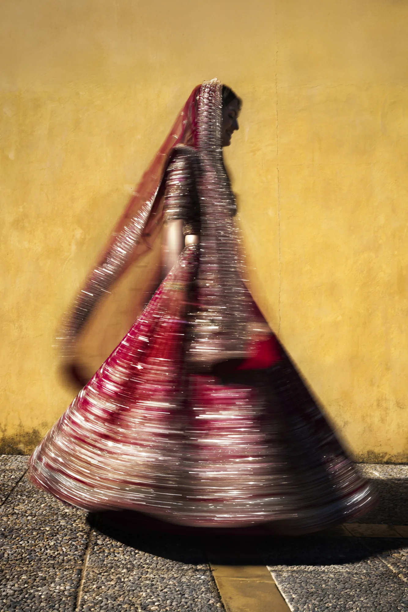 Indian bride twirling in a red lehenga against a yellow wall