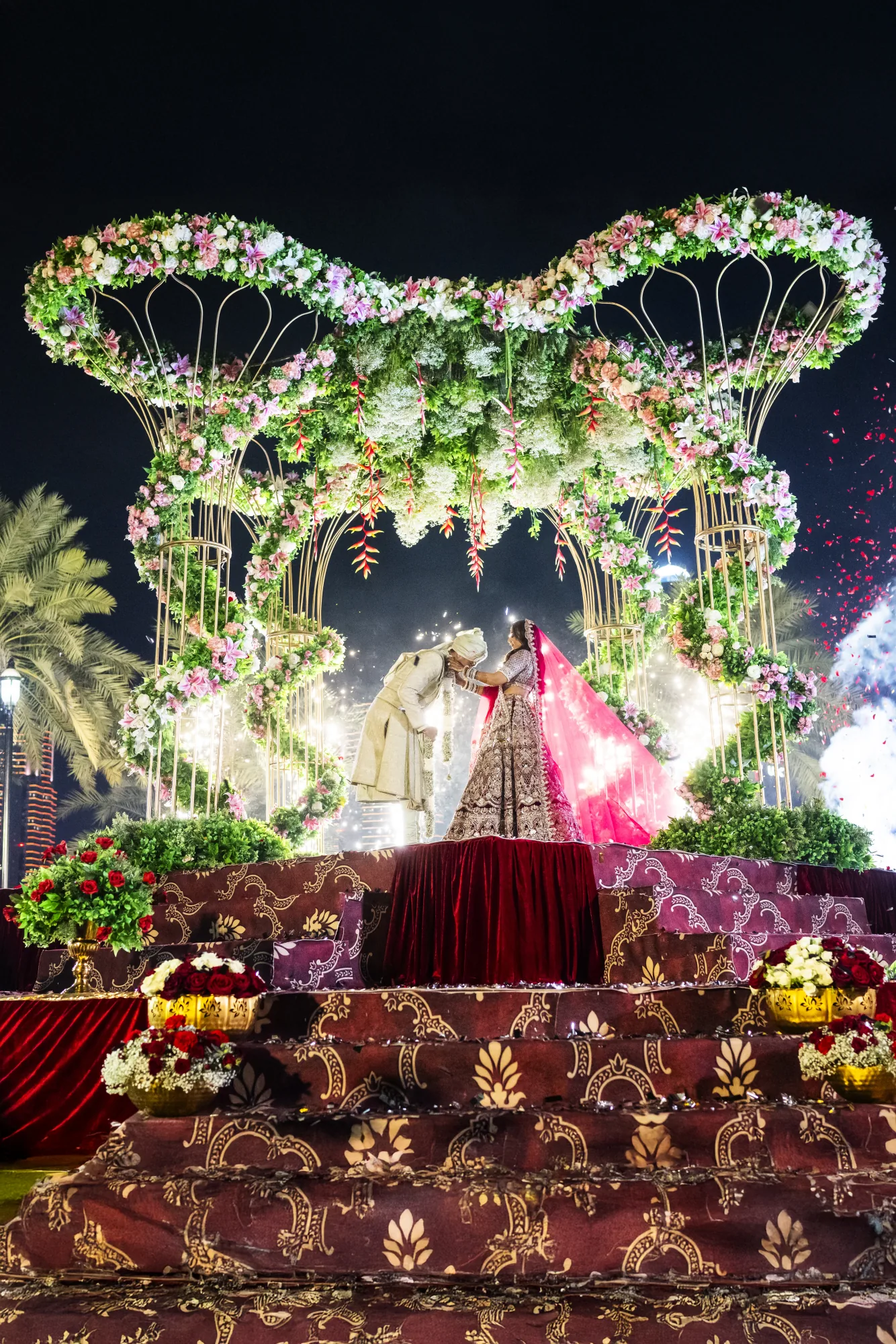 Indian wedding couple on a lavish floral stage at night