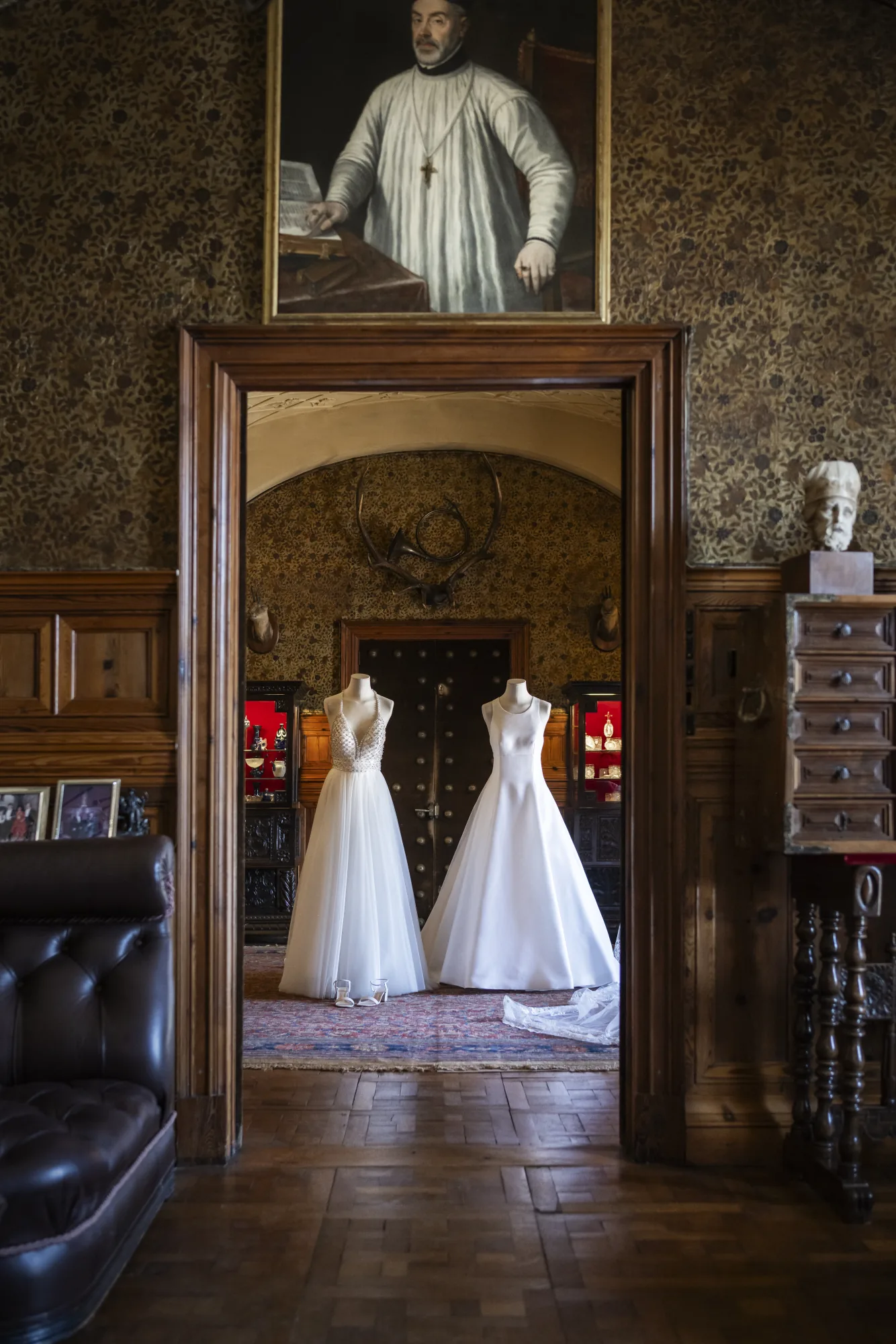 Two wedding gowns hanging in the doorway of a castle room
